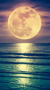 波打つ緑がかった海の上に妖艶な満月が赤い光をまとい輝いている様子を写した写真待ち受け