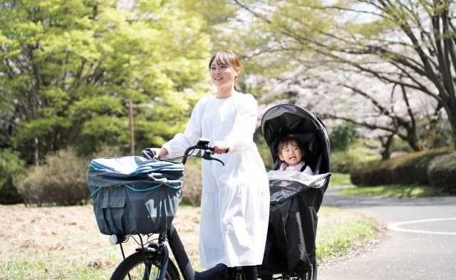 子供と自転車を二人乗りしている母親の画像