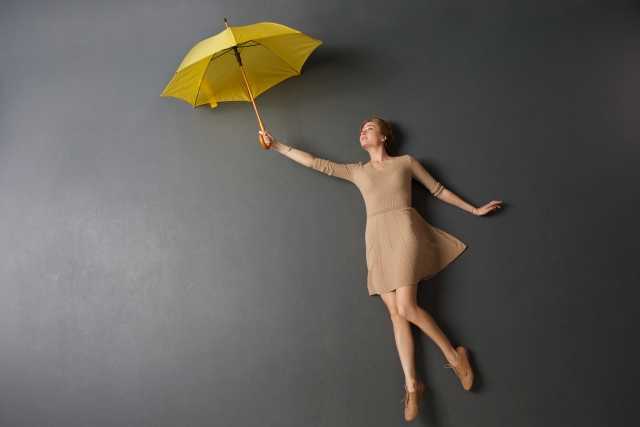 傘で空を飛ぶ女性の写真