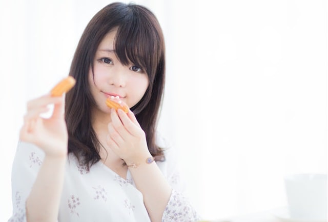 お菓子を誰かに食べさせてあげようとする女性