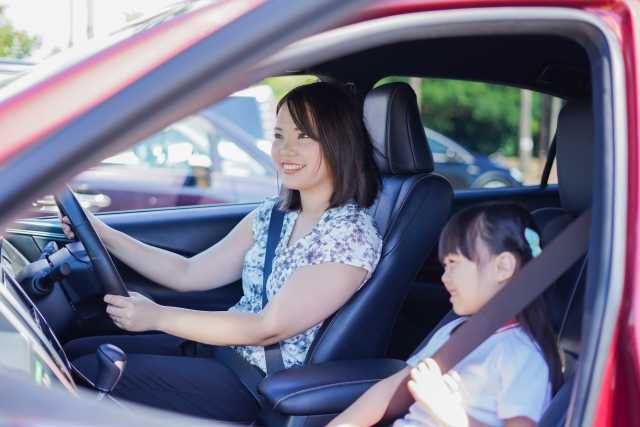 子供を乗せて運転する女性