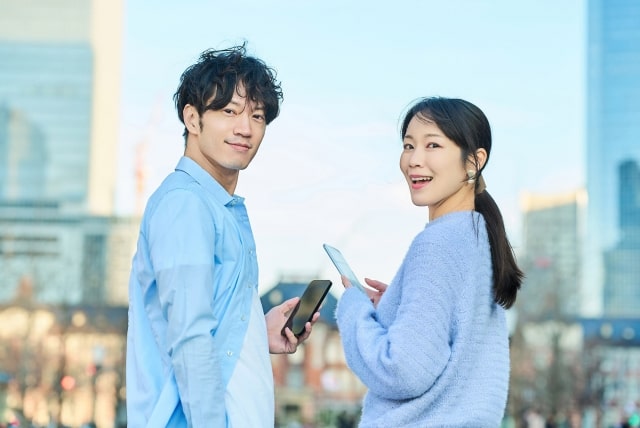 男性と女性がスマホを持って向かい合っている様子