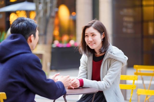 カフェのテーブルで手をにぎる男女