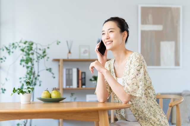 テーブルにすわって電話する女性