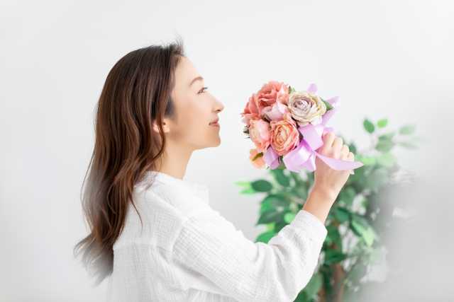花のにおいをかぐ女性