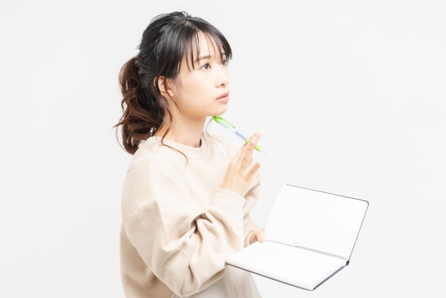 メモをとって考える女性