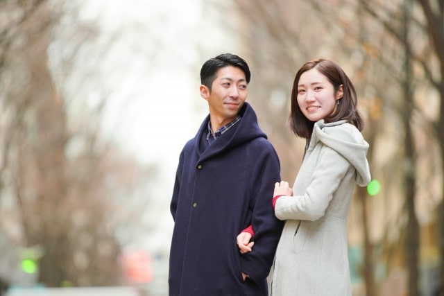腕組みをして外を歩く男女