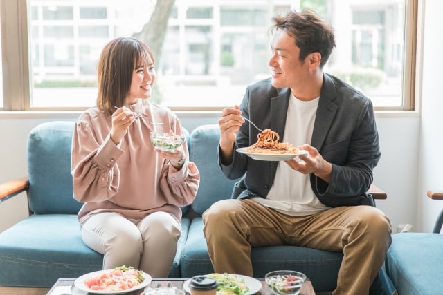 ソファに座って食事する男女