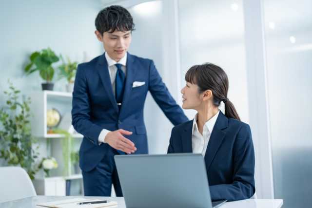 パソコン前で女性に話しかける男性ビジネスマン