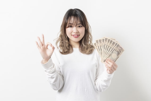 女性がお金をもって笑っている画像
