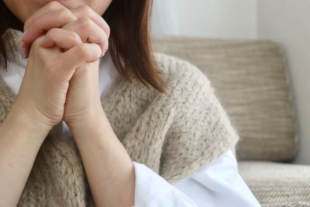 両手を目の前で組んで祈る女性のイメージ画像