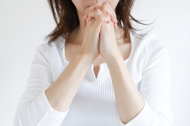 両手を組んで祈る女性のイメージ画像